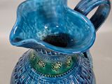 a blue and green vase with a flower inside of it