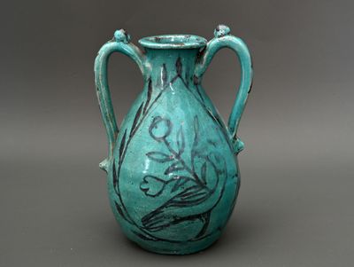 un vase bleu orné d'un oiseau, posé sur un fond gris
