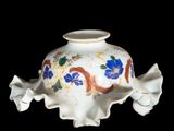a white vase with blue flowers on it on a black background