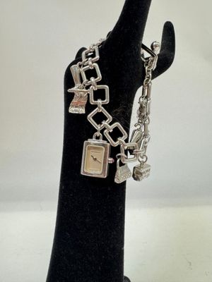 bracelet en argent avec des breloques, présenté sur une main de mannequin noire