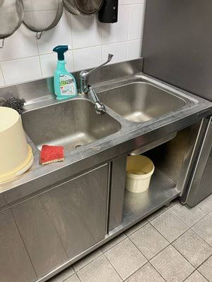 a sink and a counter in a kitchen with pots and pans hanging on the wall