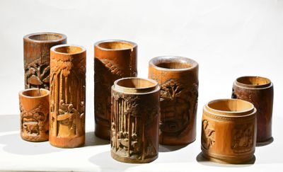 cinq vases en bois ornés de sculptures, posés sur une table