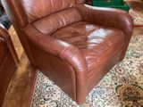 a brown leather recliner sitting on a rug in a living room