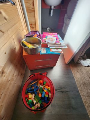 un seau rempli de Lego posé par terre à côté des toilettes