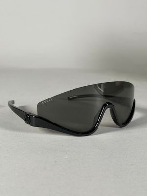 une image représentant une paire de lunettes de soleil noires posée sur une surface blanche
