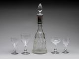 four wine glasses and a decanter on a table