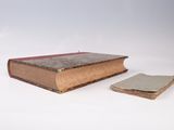 an old book with a bookmark next to it on a white surface
