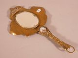 a small mirror with a gold frame on a white surface