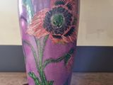 a purple vase that has a pink flower on it