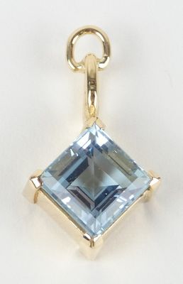 un gros plan d'un pendentif en topaze bleue sur fond blanc