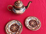 a tea pot and two small plates on a red table