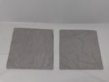 two pieces of cloth sitting on top of a bed next to each other