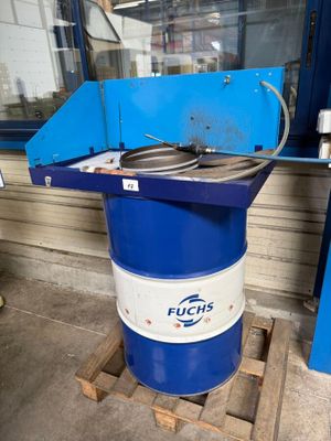 un fût bleu et blanc posé sur une palette devant une fenêtre