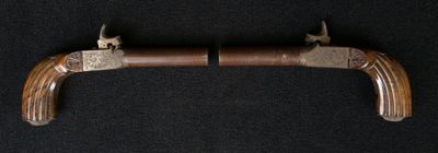 un vieux pistolet avec une crosse en bois sur fond noir