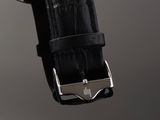 a close up of a watch with a black leather strap