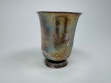 un vase en argent posé sur une surface blanche