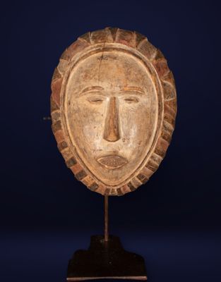 a wooden mask on a stand against a blue background