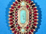 a close up of a red and green broochle on a blue surface
