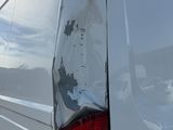 the rear end of a white van with a damaged tail light
