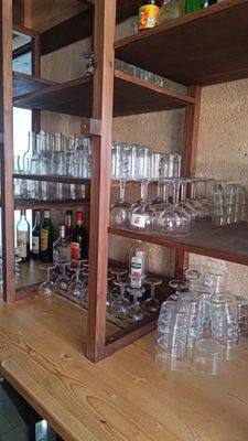 Des bouteilles et des verres sont empilés sur une étagère en bois dans un bar.
