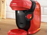 the red coffee maker is sitting on the counter next to a glass of orange juice
