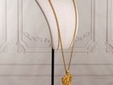 a gold necklace on a mannequin stand with a gold heart pendant