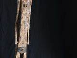 une statue en bois représentant un homme debout devant un fond noir