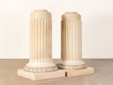 pair of white marble pedestals with columns in the middle of them