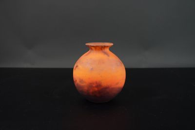 un vase orange posé sur une table noire