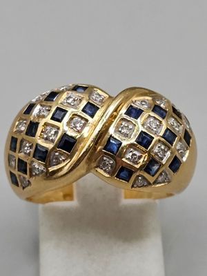 gros plan d'une bague en or avec des pierres bleues et blanches