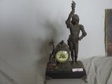 a statue of a man holding a clock on a table