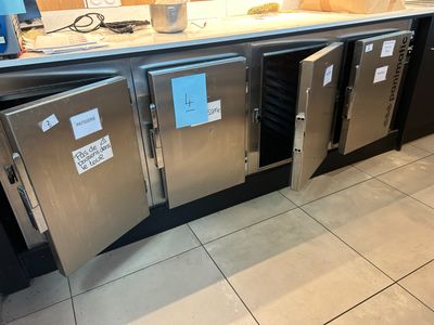 Dans une cuisine, des réfrigérateurs en acier inoxydable sont empilés les uns sur les autres