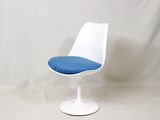 une chaise blanche sur laquelle est posé un coussin bleu