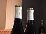 two bottles of wine sitting on a table next to each other