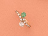 gros plan d'une bague en or avec une pierre verte et des diamants