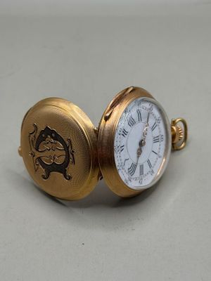 une petite montre de poche en or sur laquelle figure une horloge