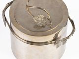 a silver container with a leaf on it on a white surface