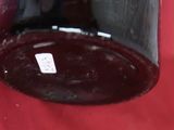 un bocal en verre muni d'une étiquette, posé sur une surface rouge