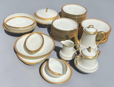 beaucoup d'assiettes et de tasses blanches et dorées sur la table