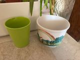 a green cup next to a white bowl on the floor