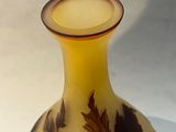 a yellow vase with leaves on it sitting on a table
