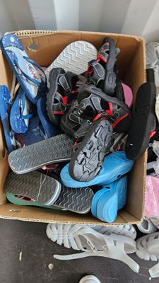 many pairs of shoes in a cardboard box on the floor