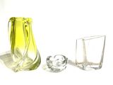 a yellow vase and two glasses on a white surface