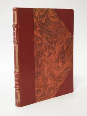 an old book with a red cover sitting on top of a white surface