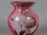 a pink vase with a bird on it on a gray surface