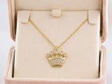 a gold necklace with a crown on it in a box