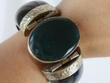 a close up of a person ' s arm with a bracelet with a green stone on it
