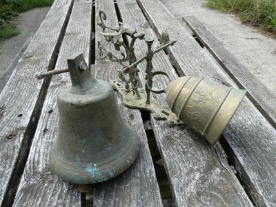 a bell sitting on a wooden bench next to a metal object