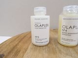 two bottles of olaplex hair products on a wooden board