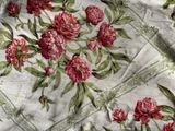 a close up of a red and green floral pattern on a white table cloth